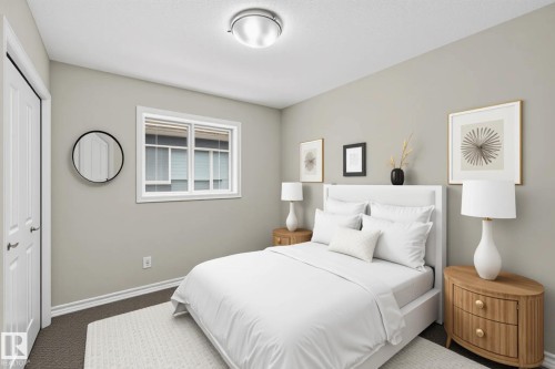 Neutral tone bedroom featuring a double window with blinds, bi-fold closet doors, wall-to-wall carpeting, and a flush-mount ceiling light fixture - 2460 15 Avenue, Edmonton, AB 
