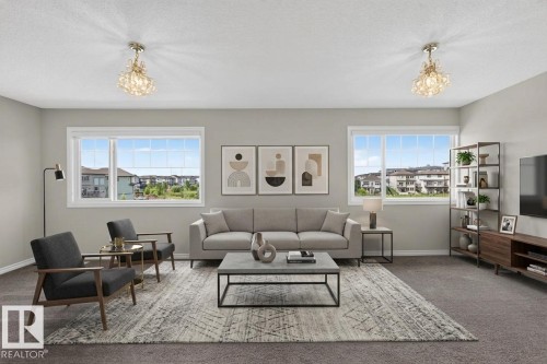 Spacious living area featuring two large windows, dual ornate ceiling light fixtures, and neutral wall tones - 2460 15 Avenue Nw, Edmonton, AB - Indoor Photo Showing Living Room