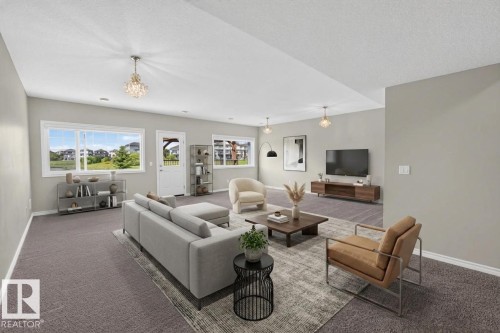 Spacious living area featuring neutral carpeting, multiple windows, a white paneled door, and recessed lighting - 2460 15 Avenue Nw, Edmonton, AB - Indoor Photo Showing Living Room