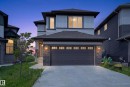 Contemporary two-story exterior featuring a double garage, stone accents, horizontal siding, a covered front entry, and a concrete driveway - 2460 15 Avenue, Edmonton, AB 