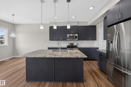 Kitchen featuring wood-finish flooring, dark cabinetry, and light-toned countertops - 2460 15 Avenue, Edmonton, AB 