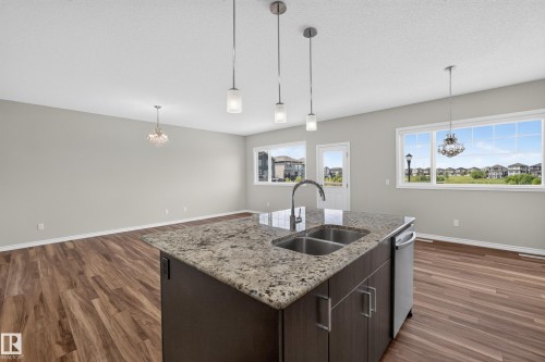 Open-concept living space featuring wood-finish flooring and light gray walls - 2460 15 Avenue, Edmonton, AB 