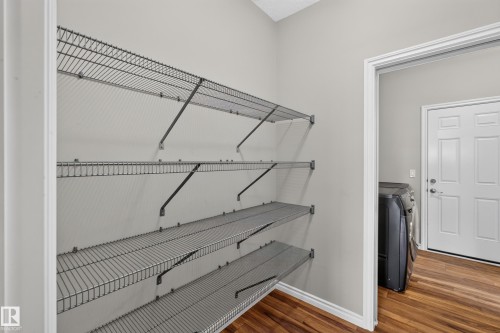 Utility space featuring wire shelving, wood-finish flooring, light grey walls, and white trim - 2460 15 Avenue, Edmonton, AB 