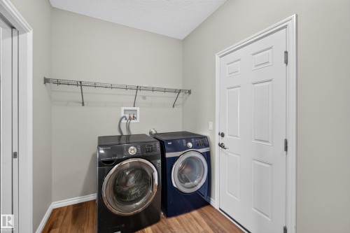 Dedicated laundry space featuring wood-finish flooring, light neutral wall paint, and a wire shelving unit - 2460 15 Avenue, Edmonton, AB 
