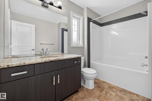 Bathroom featuring a dark wood-finish vanity with a granite countertop, undermount sink, and chrome faucet - 2460 15 Avenue, Edmonton, AB 