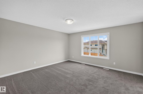 Expansive room featuring neutral wall tones, gray carpet flooring, and white trim - 2460 15 Avenue, Edmonton, AB 