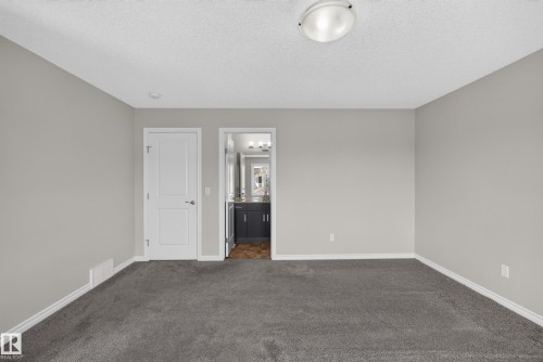 Carpeted room with light gray walls, white trim, and a semi-flush mount ceiling light - 2460 15 Avenue, Edmonton, AB 