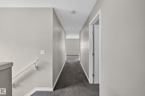 Hallway featuring neutral wall tones, contrasting white trim, recessed lighting, and dark carpet flooring - 2460 15 Avenue, Edmonton, AB 