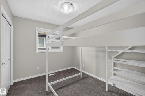 Carpeted room featuring a white interior door, a single window, and a flush mount ceiling light - 2460 15 Avenue, Edmonton, AB 