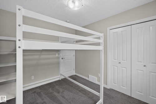 Bedroom featuring neutral wall paint, gray carpeting, a built-in shelving unit, and bifold closet doors - 2460 15 Avenue, Edmonton, AB 