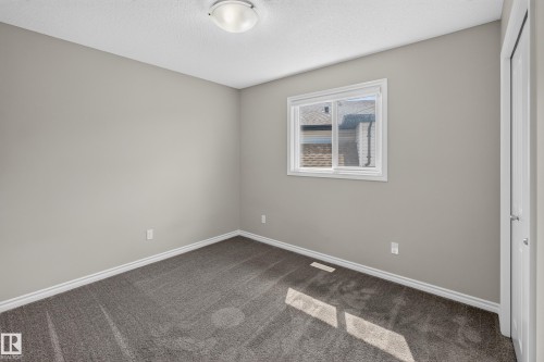 Room featuring neutral grey wall paint, plush grey carpeting, white trim, a double-paned window, and a ceiling-mounted light fixture - 2460 15 Avenue, Edmonton, AB 