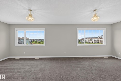 Spacious room featuring neutral grey walls and dark grey carpeting - 2460 15 Avenue, Edmonton, AB 