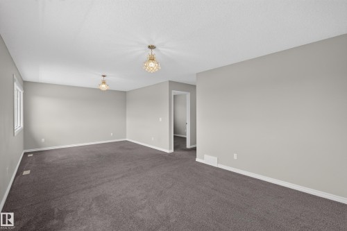 Spacious interior featuring neutral gray wall paint and dark gray carpeting - 2460 15 Avenue, Edmonton, AB 