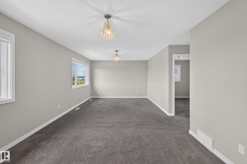 Spacious room featuring gray carpeting, light gray walls, white trim, and two windows - 2460 15 Avenue, Edmonton, AB 