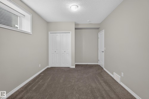 Neutral gray wall paint with white trim, brown carpet, and a white bi-fold closet door - 2460 15 Avenue, Edmonton, AB 