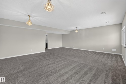 Spacious room featuring gray wall-to-wall carpeting, light gray wall paint, and white baseboards - 2460 15 Avenue, Edmonton, AB 