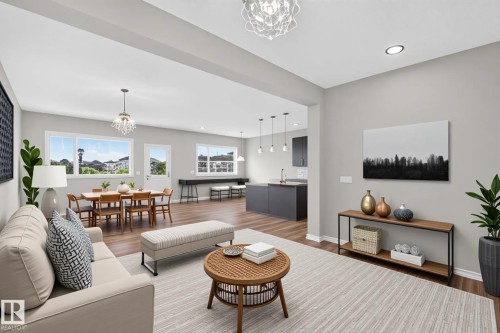 Expansive living area featuring wood-finish flooring, recessed lighting, and a decorative chandelier - 2460 15 Avenue, Edmonton, AB 