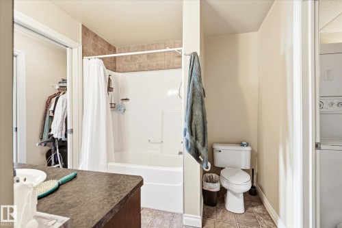 Bathroom featuring a combination bathtub and shower with subway tile surround, a single vanity with dark countertop, and a tiled floor - 402 10121 80 Avenue, Edmonton, AB 
