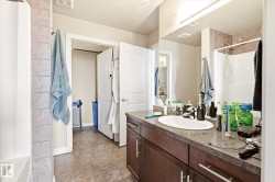 Bathroom featuring a dark wood-finish vanity with an integrated sink, a large mirror, and tiled flooring - 