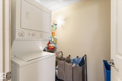Dedicated laundry area featuring a white stacked washer and dryer, a recessed shelf, and a wall-mounted light fixture - 