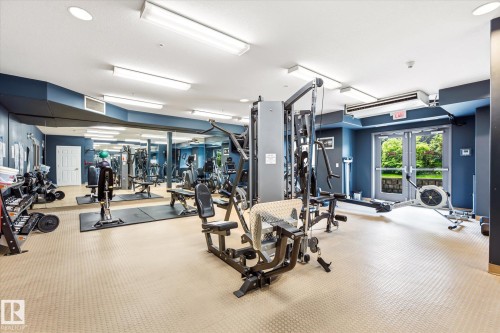 Fitness center featuring various exercise equipment, wall-mounted mirrors, recessed lighting, and exterior access via double glass doors - 402 10121 80 Avenue, Edmonton, AB 