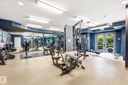 Fitness center featuring various exercise equipment, wall-mounted mirrors, recessed lighting, and exterior access via double glass doors - 
