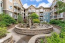 Central courtyard featuring a tiered stone fountain, surrounding rock garden, and meandering concrete pathways - 402 10121 80 Avenue, Edmonton, AB 