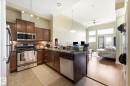 Open-concept kitchen and living area featuring high ceilings, dark wood-finish cabinetry, and stainless steel appliances - 402 10121 80 Avenue, Edmonton, AB 