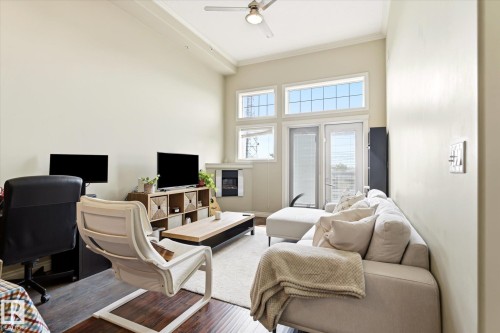 Spacious living area featuring high ceilings, light-toned walls, and wood-finish flooring - 402 10121 80 Avenue, Edmonton, AB 