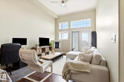 Spacious living area featuring high ceilings, light-toned walls, and wood-finish flooring - 