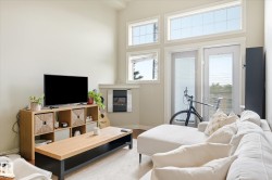 Living area featuring high ceilings, a wall-mounted fireplace, and light-toned walls - 