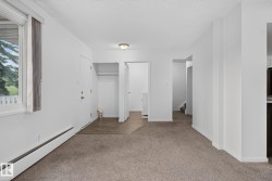 Light-filled room featuring neutral-toned carpeting, a window with vertical blinds, and white baseboards - 