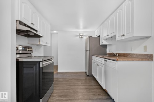 Galley kitchen with white cabinetry and wood-finish flooring - 401 2908 116A Avenue, Edmonton, AB 