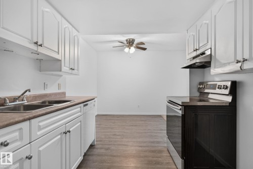 Kitchen featuring white cabinetry, a double basin sink, and a white dishwasher - 401 2908 116A Avenue, Edmonton, AB 