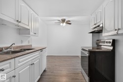 Kitchen featuring white cabinetry, a double basin sink, and a white dishwasher - 