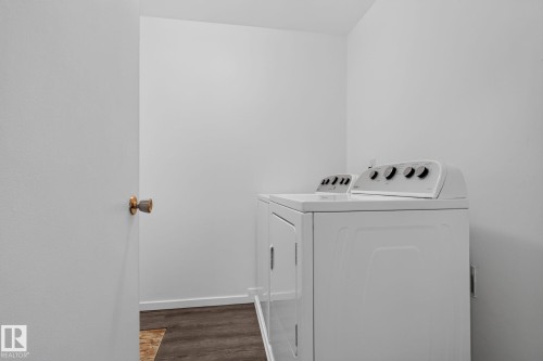 Dedicated laundry area featuring white walls, dark wood-finish flooring, and white baseboards - 401 2908 116A Avenue, Edmonton, AB 