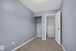 Neutral gray walls with textured ceiling and a built-in closet featuring two natural wood shelves - 