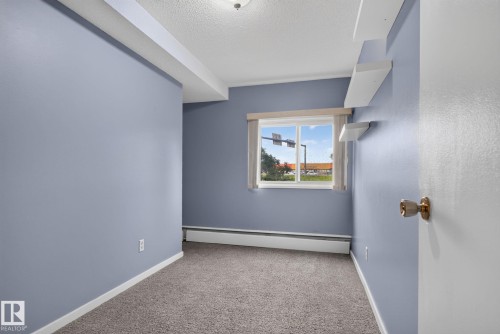 Room with light blue walls, gray carpet, white trim, and a window featuring white horizontal blinds - 401 2908 116A Avenue, Edmonton, AB 