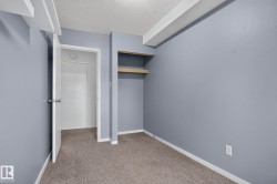Interior room featuring light grey walls, textured ceiling, light brown carpet, and white trim - 