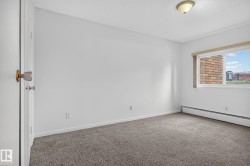 Neutral-toned room featuring a window with a valance, baseboard heating, textured ceiling, and gray carpet flooring - 