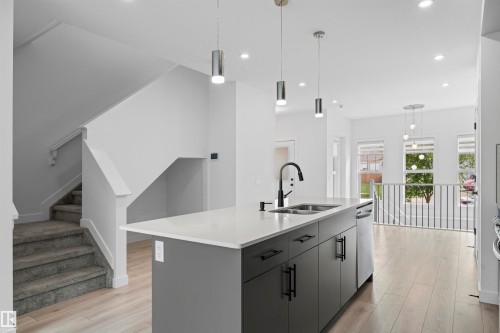 Modern kitchen island featuring a white countertop, matte gray cabinetry, and a black faucet - 2953 Coughlan Green Green, Edmonton, AB 