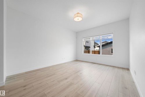 Open room featuring light wood-finish flooring, white walls, and a multi-pane window with white trim - 2953 Coughlan Green Green, Edmonton, AB 