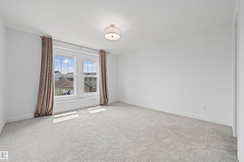 Bright room featuring a pair of windows with white trim, light-toned carpeting, and a flush-mount ceiling light fixture - 2953 Coughlan Green Green, Edmonton, AB 