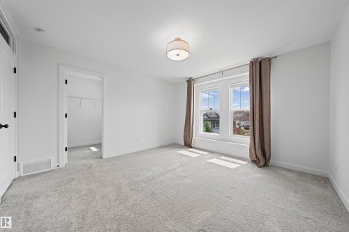 Bright interior space with light gray carpeting, crisp white walls, and a contemporary drum pendant light fixture - 2953 Coughlan Green Green, Edmonton, AB 