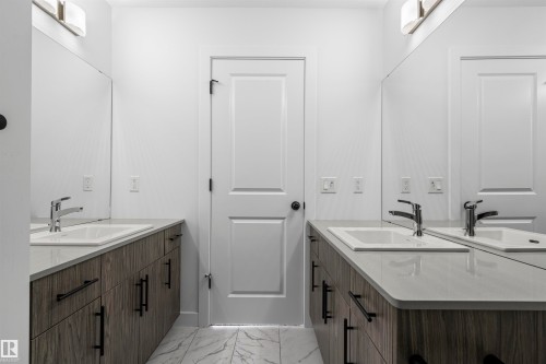 Dual vanity featuring light wood-finish cabinetry, light-toned countertops, and undermount sinks with chrome faucets - 2953 Coughlan Green Green, Edmonton, AB 