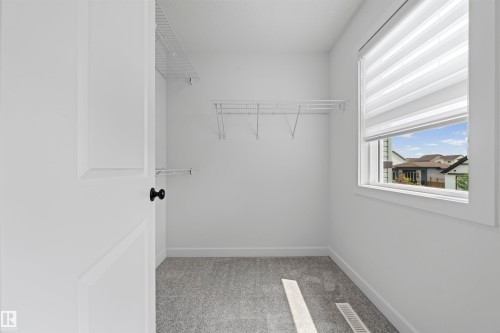 Walk-in closet featuring white wire shelving, grey carpet, and a window with blinds - 2953 Coughlan Green Green, Edmonton, AB 