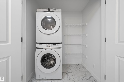 Dedicated laundry alcove featuring a stacked washer and dryer, white wire shelving, and light-toned tile flooring - 2953 Coughlan Green Green, Edmonton, AB 
