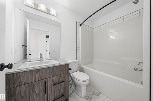 Bathroom featuring a wood-finish vanity with a single basin sink and a large wall-mounted mirror - 2953 Coughlan Green Green, Edmonton, AB 