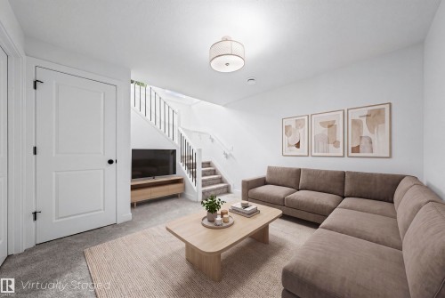 Bright living area featuring white walls, a staircase with black metal balusters, and grey carpeting - 2953 Coughlan Green Green, Edmonton, AB 