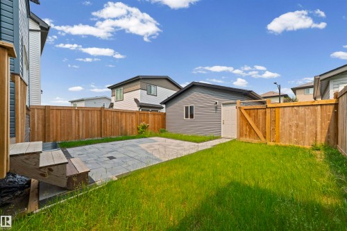 Expansive backyard featuring a paver patio area, green lawn, full wood fencing, and a detached structure with siding and a window - 2953 Coughlan Green Green, Edmonton, AB 
